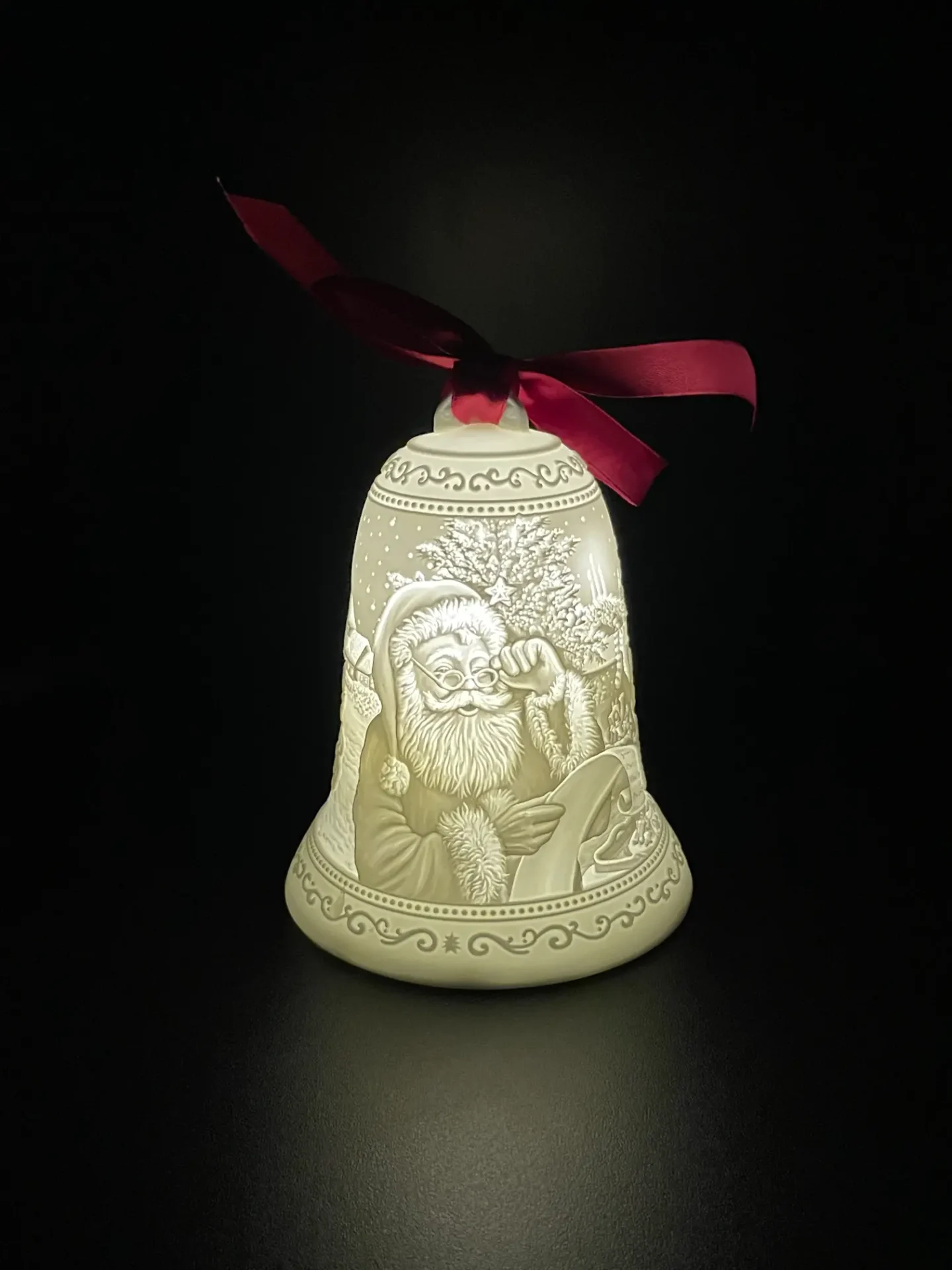 A lighted bell with santa claus and christmas tree.